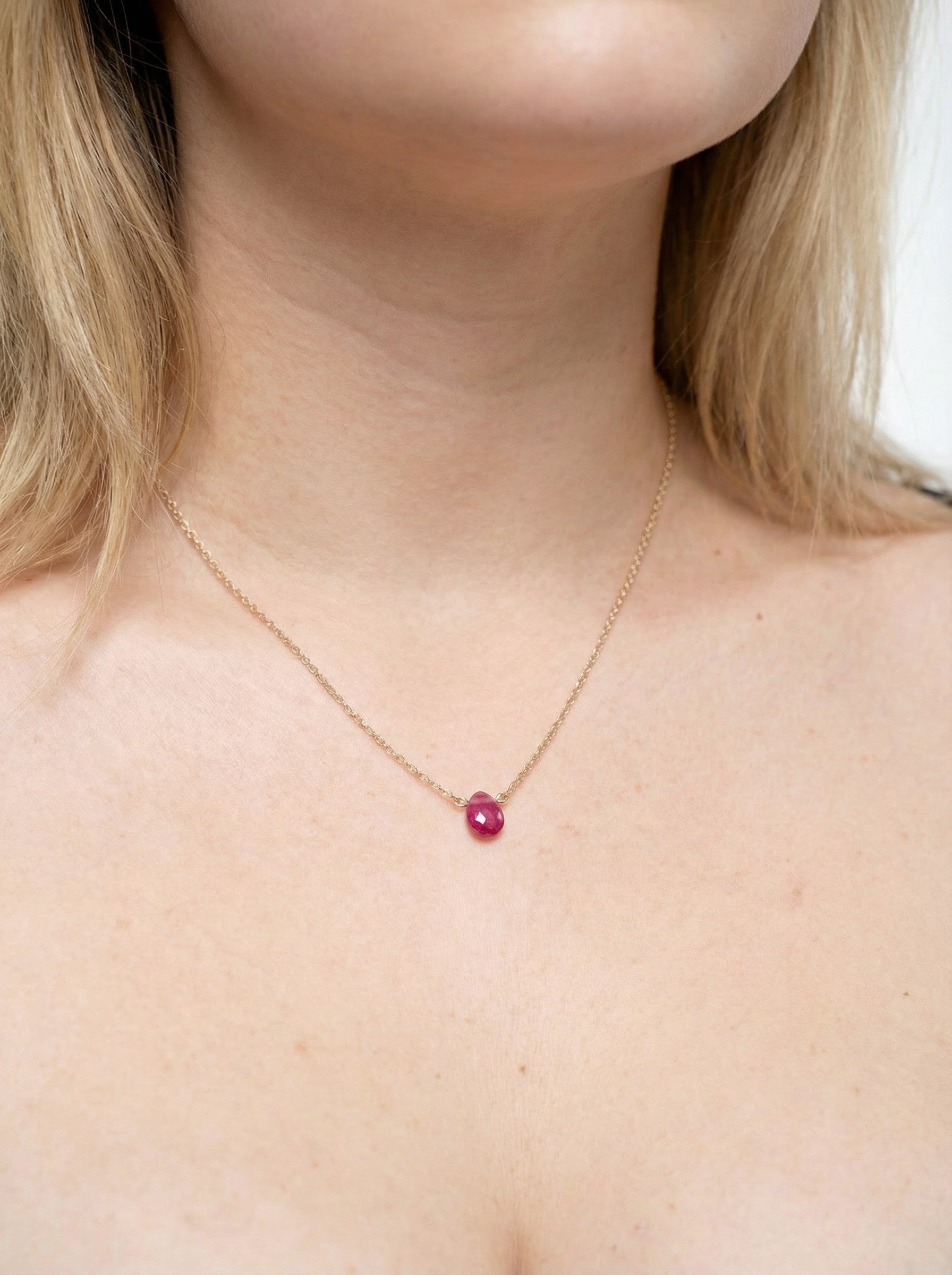 Necklace with a Pink Sapphire gemstone worn by a person with blonde hair.