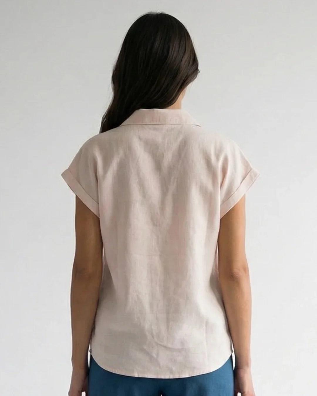 Woman wearing a light pink short-sleeve ethical shirt from Reca, viewed from the back
