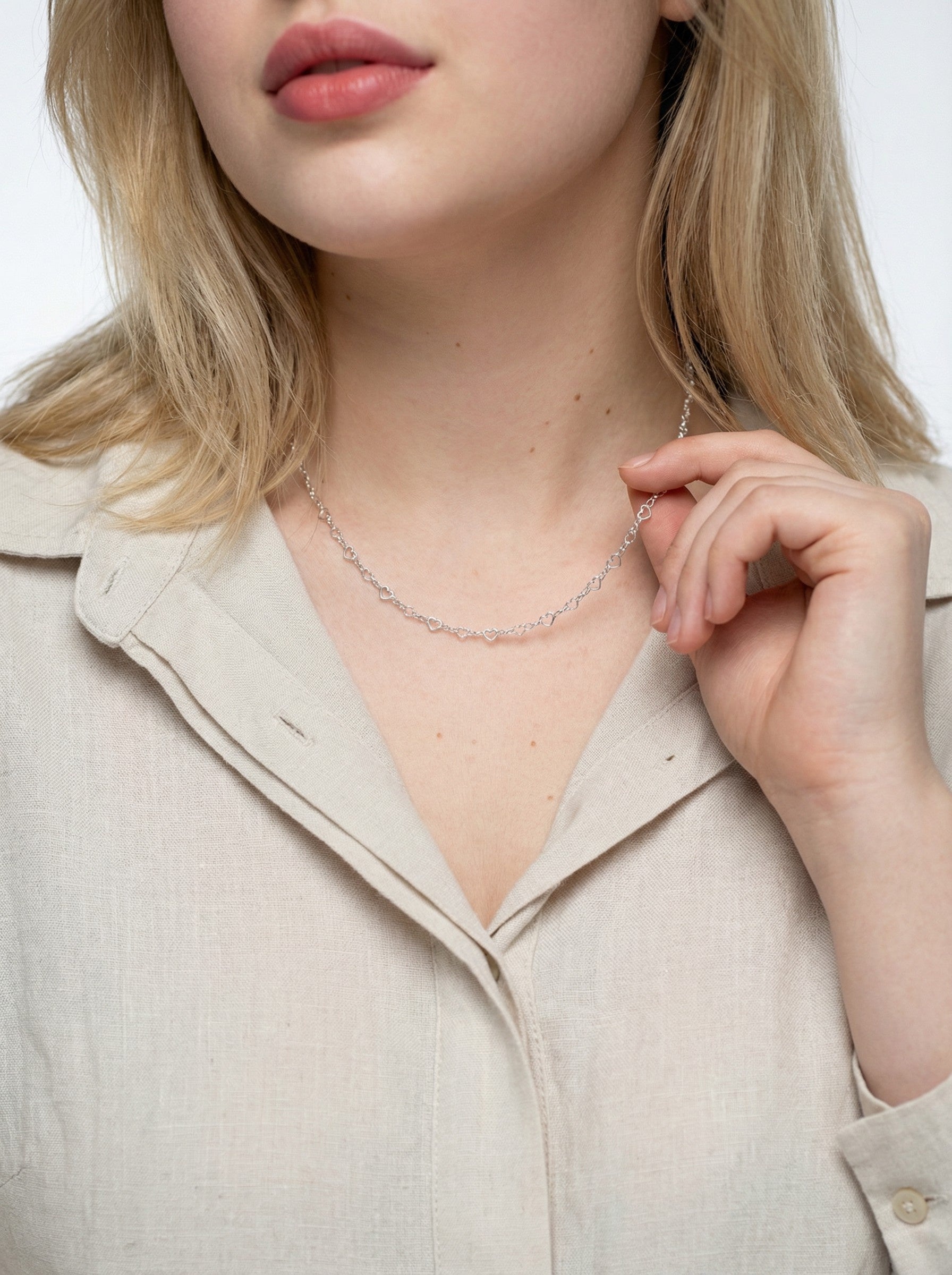 Woman wearing a delicate Silver Heart Link Chain necklace with a plain background