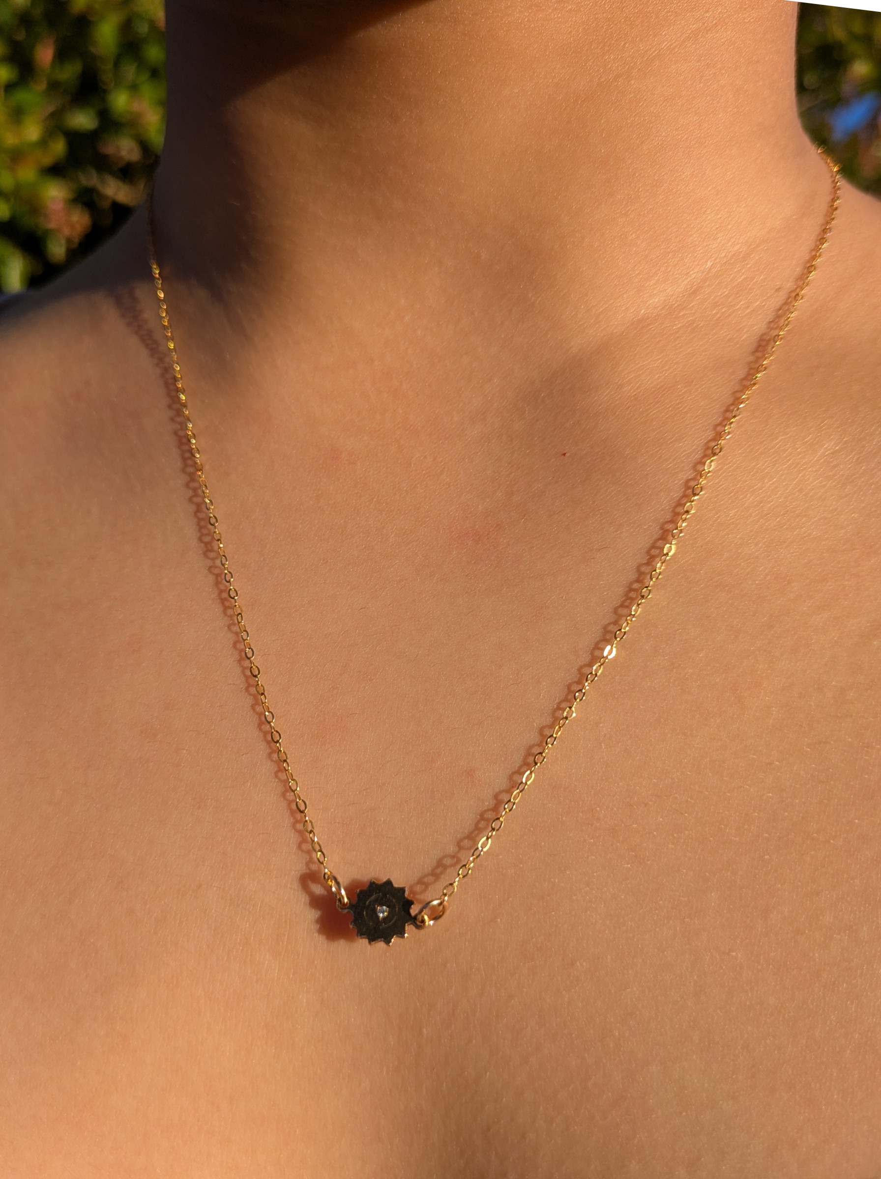 Gold chain necklace with small black floral pendant, Reca ethical jewellery on model's neck