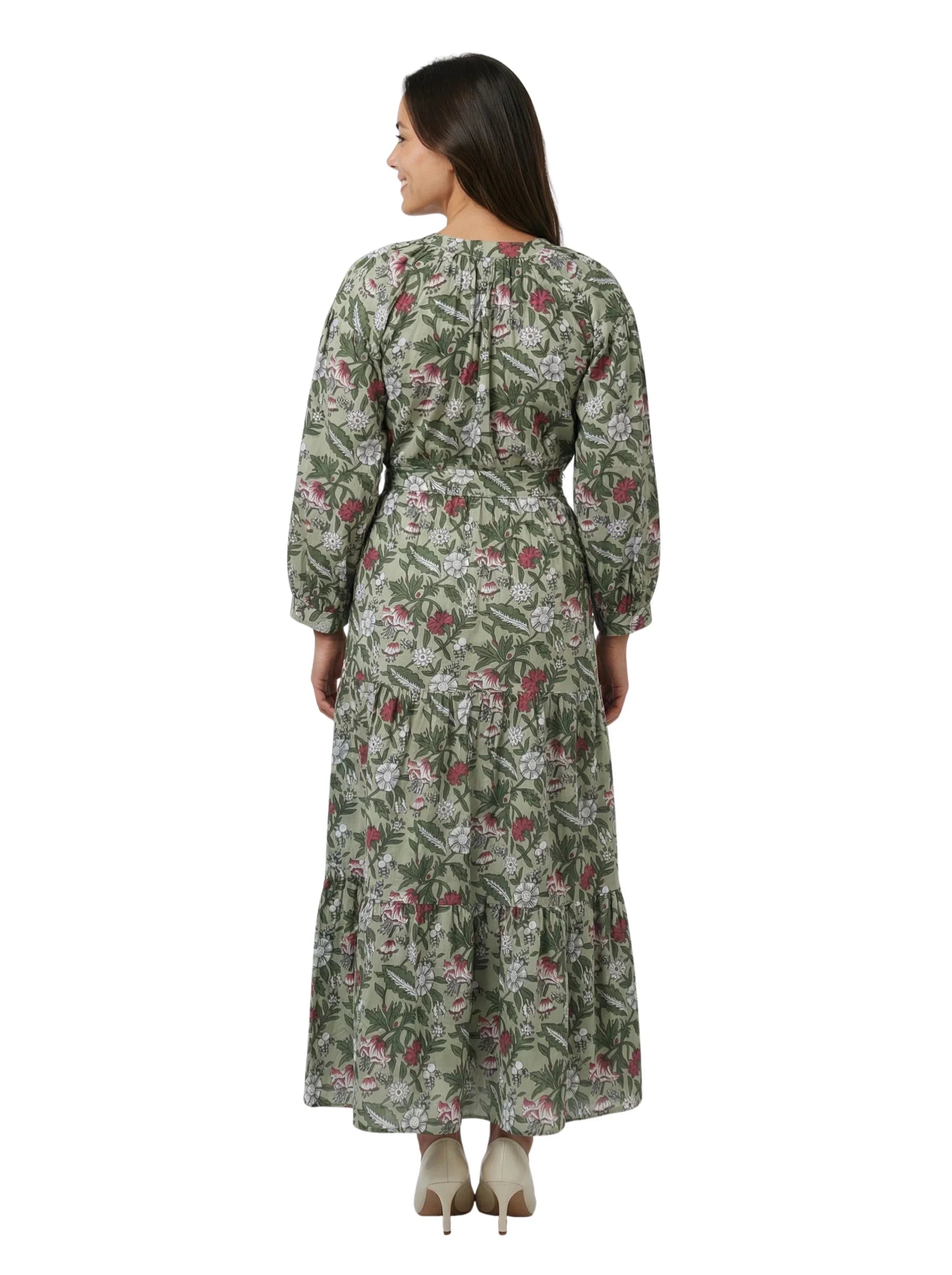 Woman wearing an ethical Reca gold necklace with THE CAMILLE DRESS – GREEN FLORAL. The model is facing away from the camera, showing the back of the dress and the natural drape of the fabric. Her head is slightly turned to the side so the Reca gold necklace is subtly visible. Clean, simple background with soft natural light. Minimalist fashion editorial style.