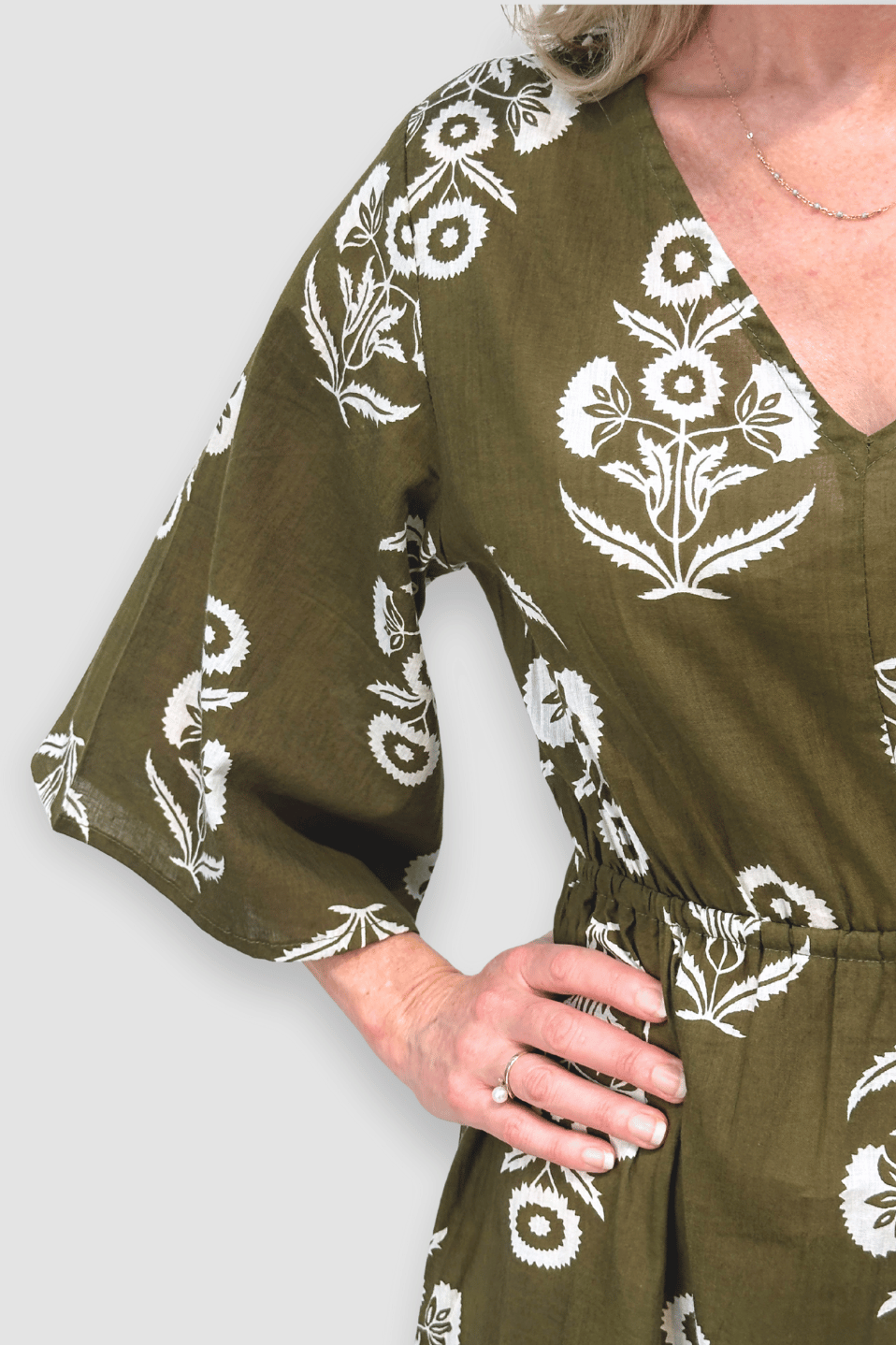 Green dress with white floral patterns worn by a person on a light gray background
