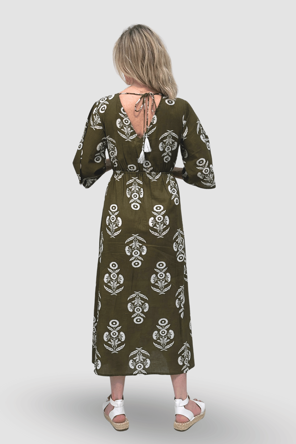 Woman wearing a green patterned dress on a white background with back details