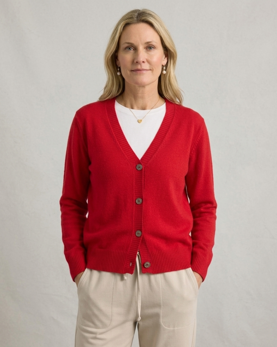 Woman wearing the red Cashmere-Merino cardigan buttoned over a white tee with cream trousers, front view