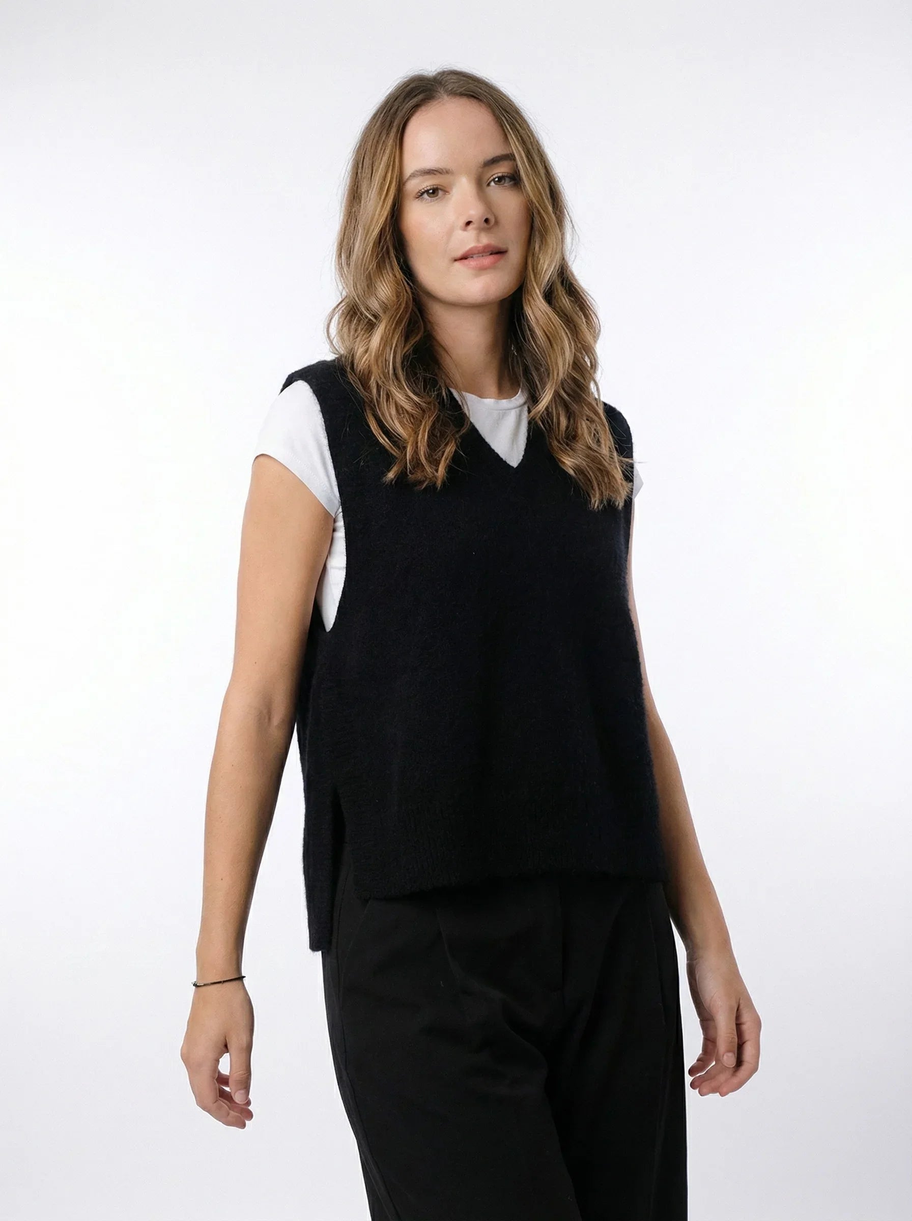 Woman wearing a Possum Merino Ride Vest - Black over a white t-shirt and black pants