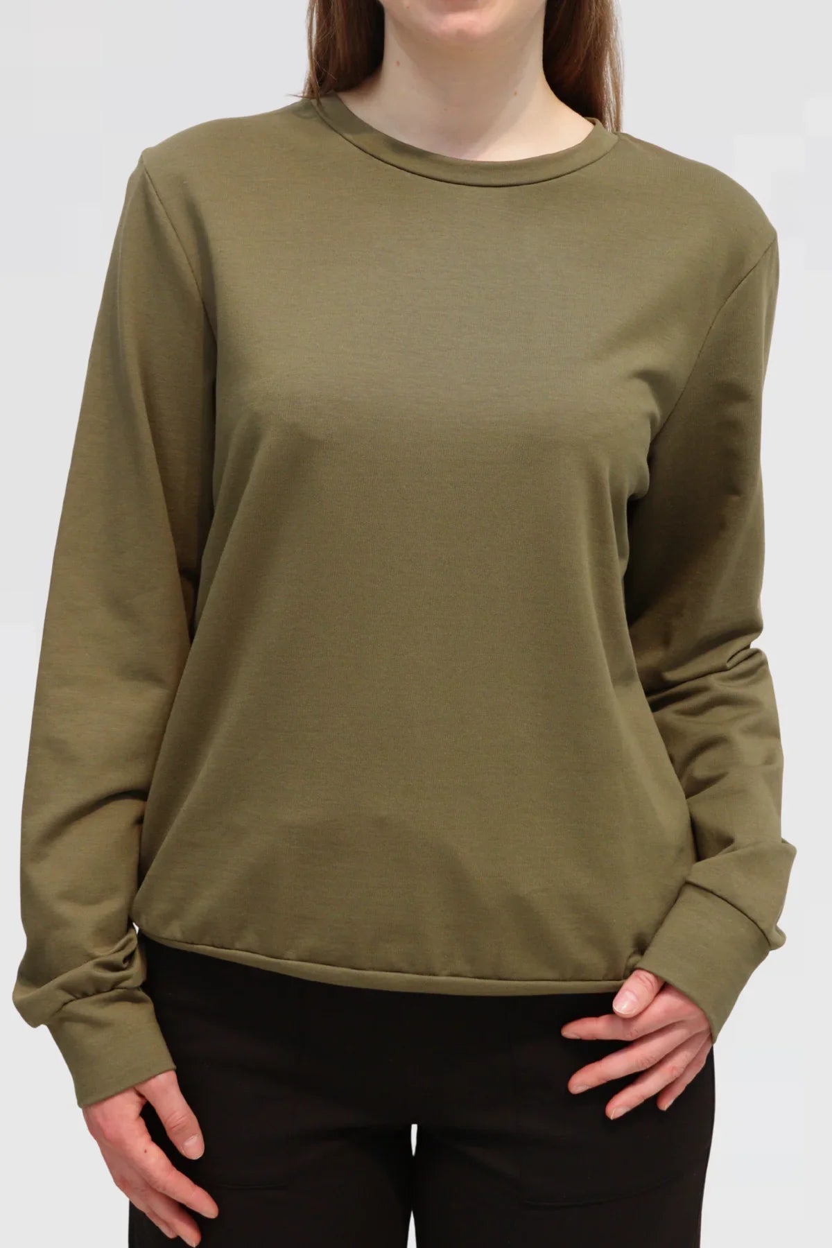 Model wearing Reca olive Organic Cotton Sweater with black wide-leg trousers, angled front view.