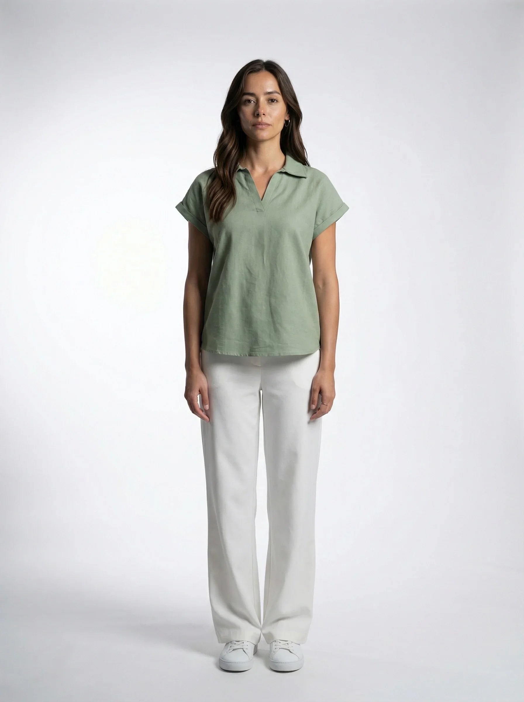 Woman in a sage green short sleeve top and white trousers, ethical Reca clothing fashion