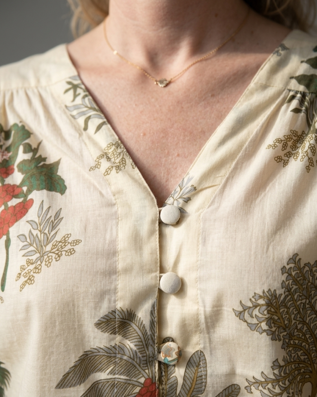 V-neckline and fabric-covered button detail on the Palm Garden Cotton Blouse