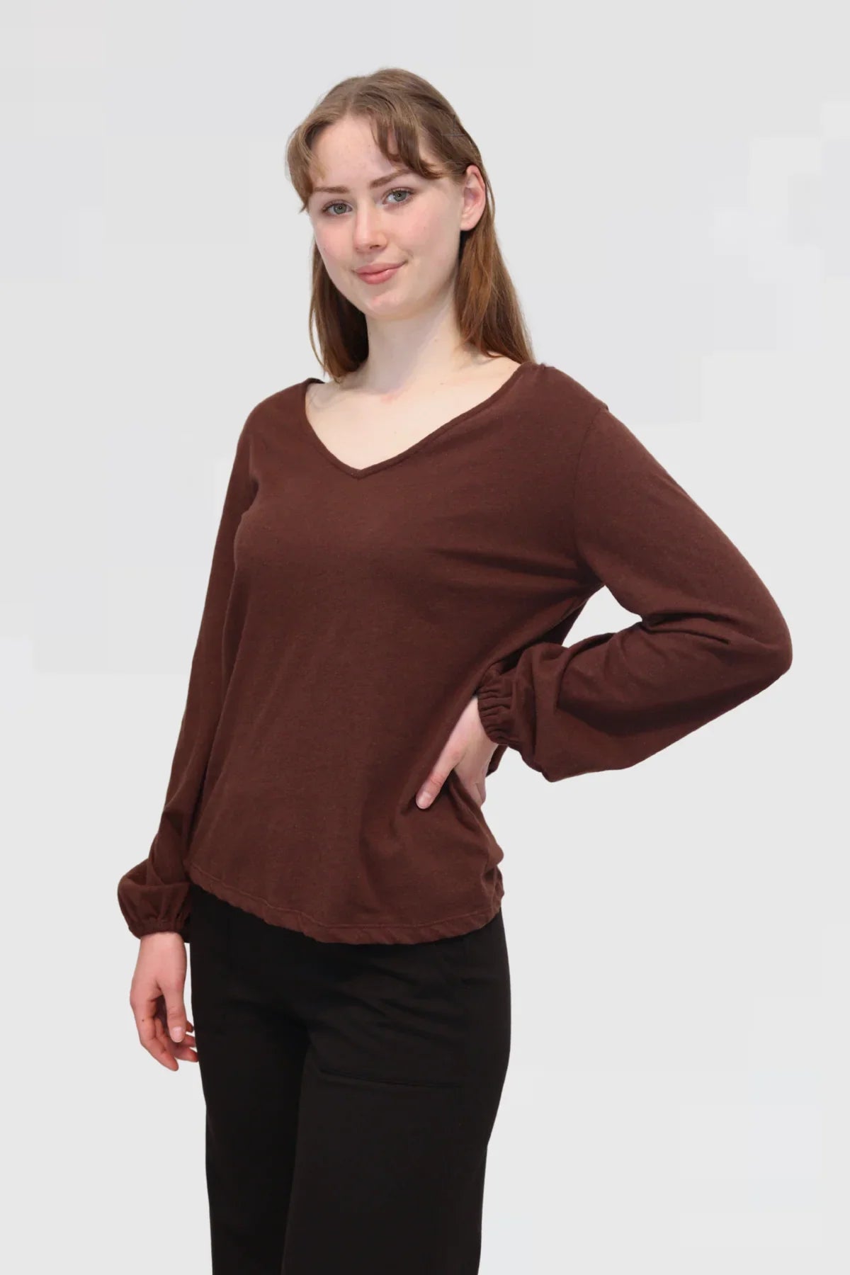 Model wearing Reca Bishop Blouse in Redwood, angled front view highlighting relaxed fit and bishop sleeves.