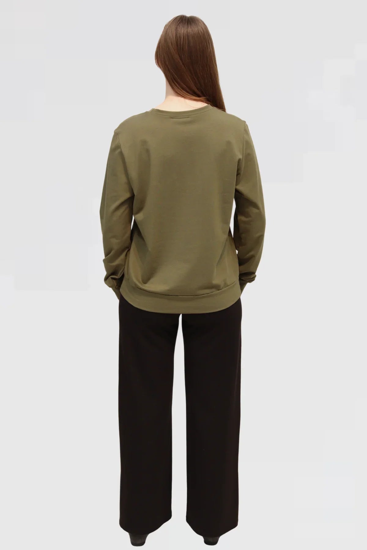 Back view of Reca Organic Cotton Sweater in olive paired with black drape trousers, relaxed fit.