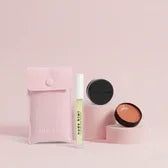 Nude Kiwi Lip Plump Hydrating Serum and Moisture Lock Lip Balm set with pink pouch on a pink background