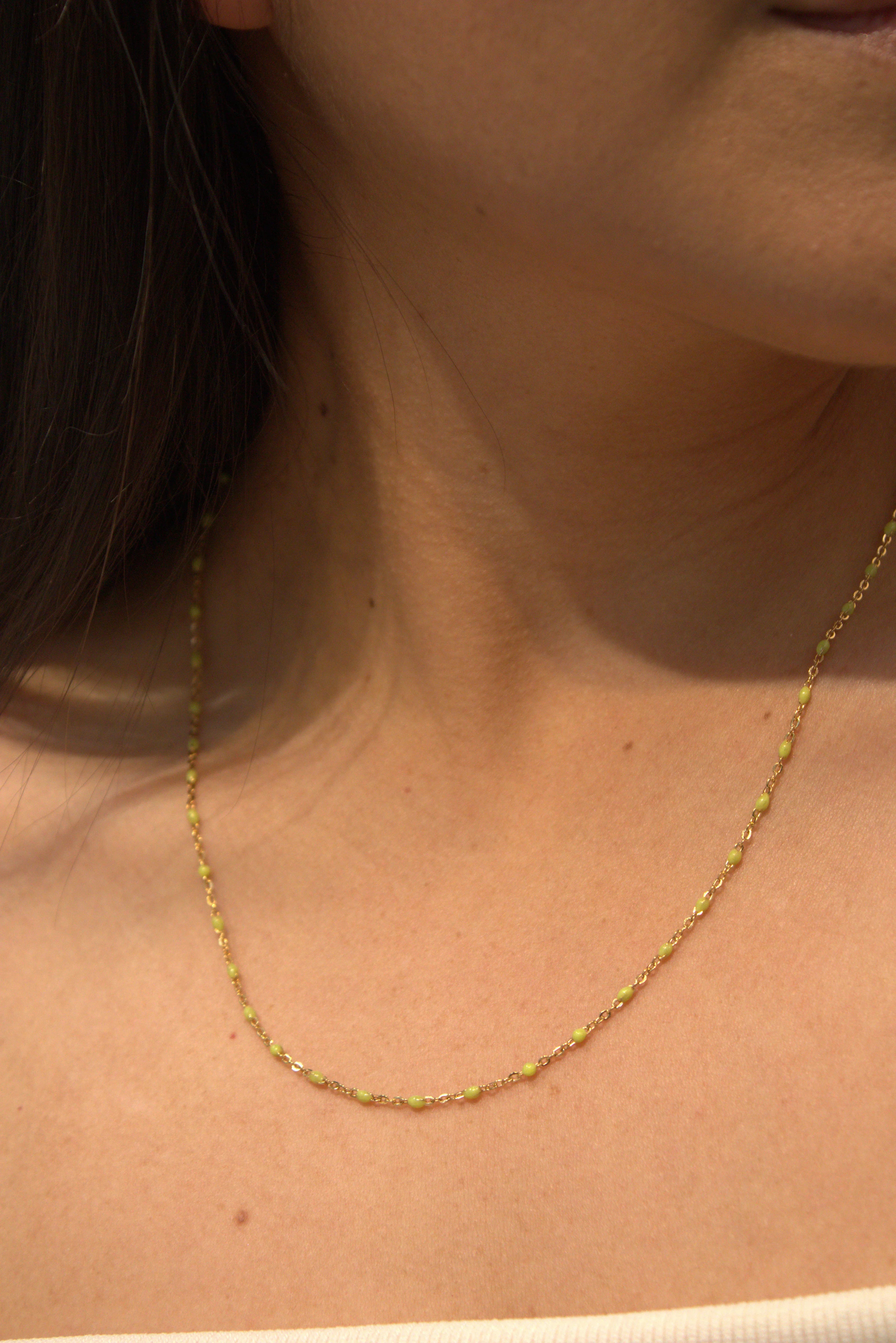 Close-up of a person wearing a delicate gold necklace.