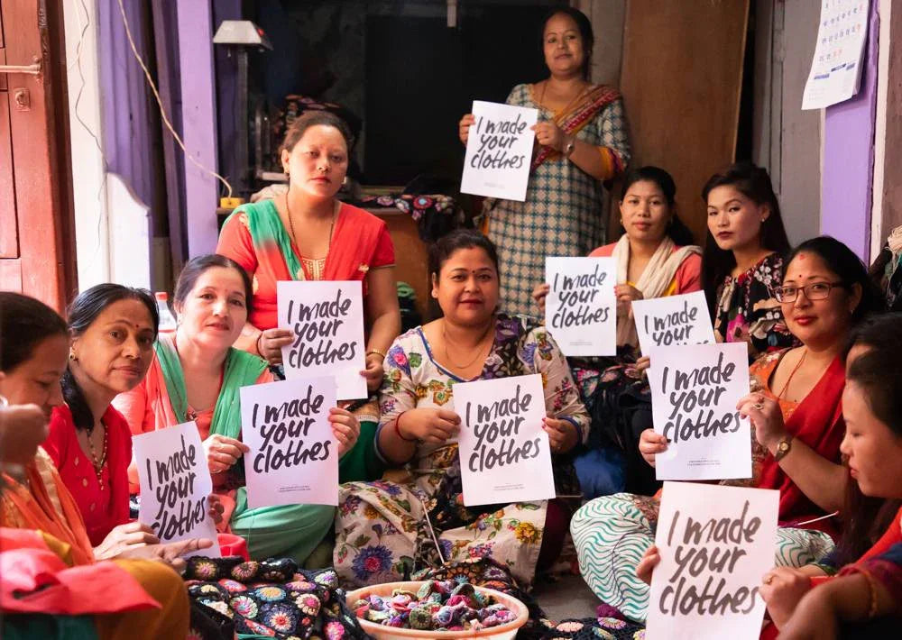 Women from the Reca manufacturing team proudly holding signs that say "I made your clothes."