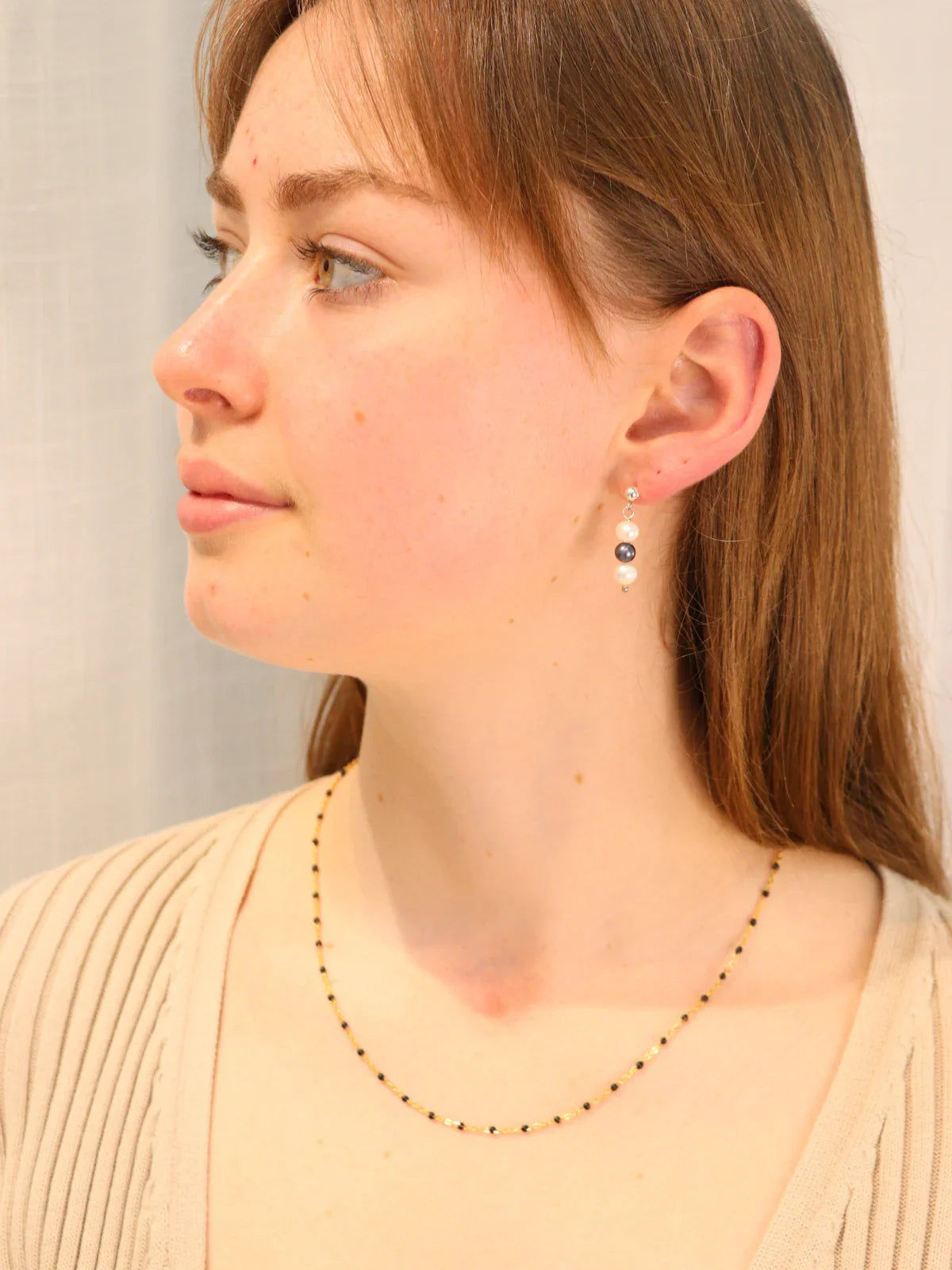 Model wearing elegant triple pearl drop earrings with white and black freshwater pearls, handcrafted in New Zealand.
