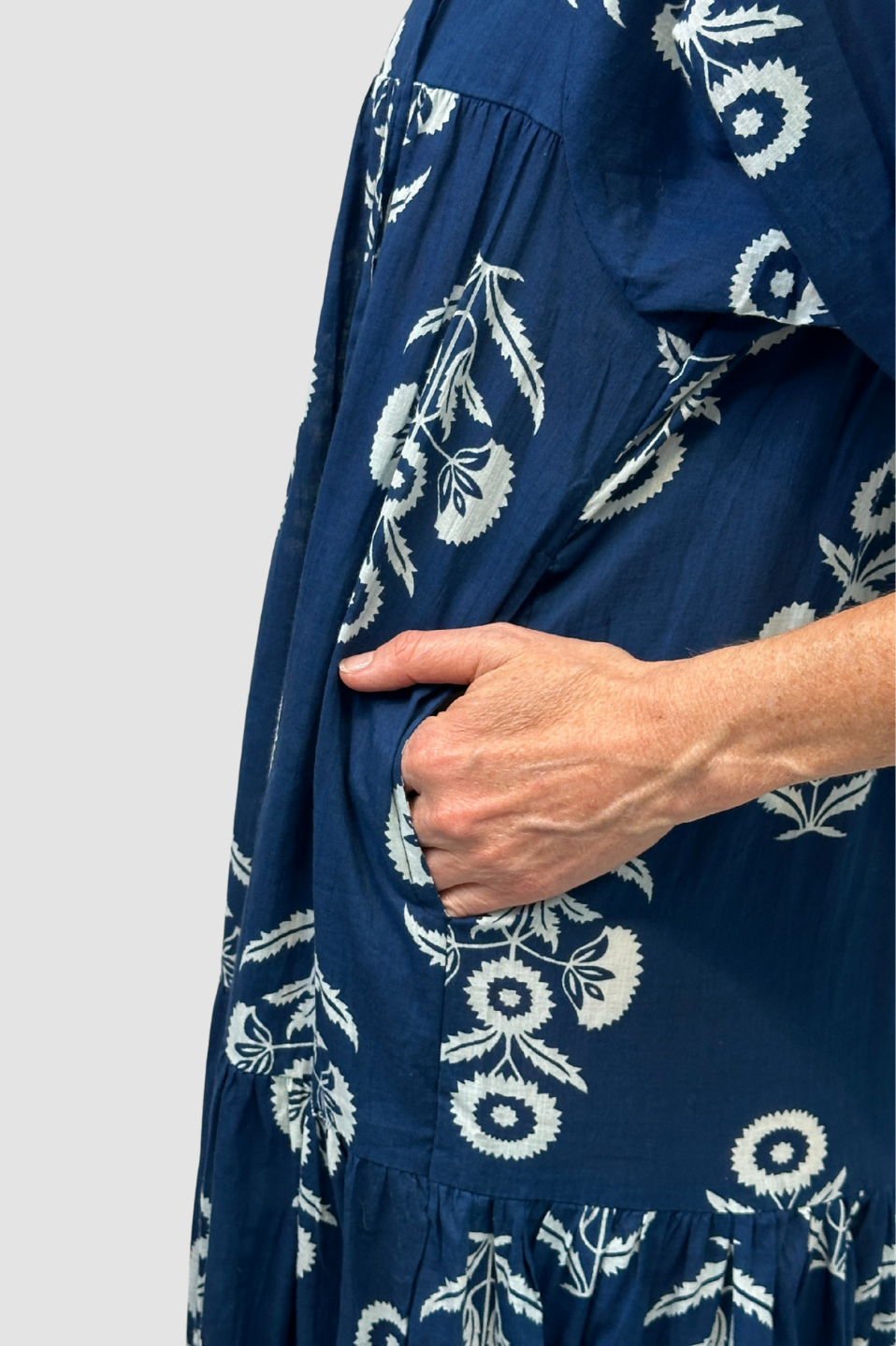 Navy blue dress with white floral pattern worn by a person on a light gray background