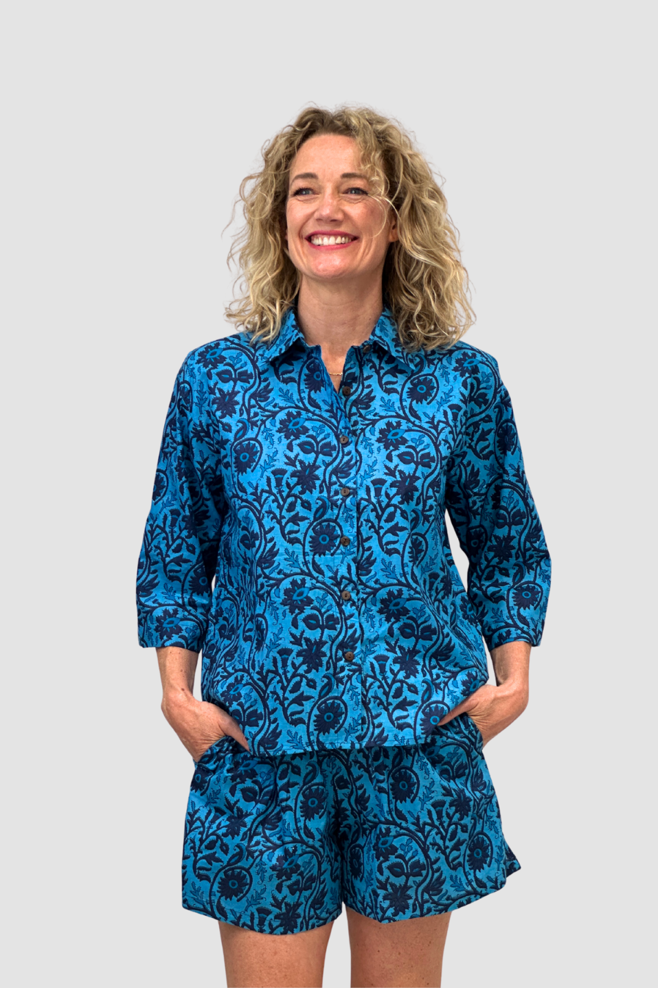 Woman wearing a blue floral outfit, named the "Indigo Tide Cotton Lounge Shorts" against a gray background