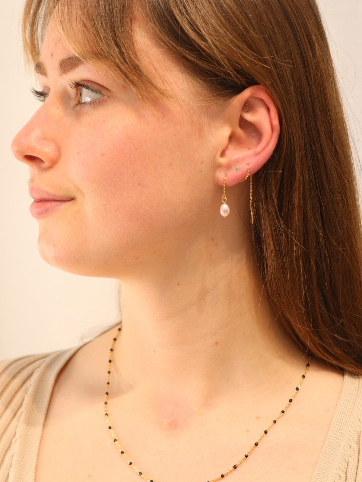 Woman wearing gold chain threader earrings with pink freshwater pearl, dainty and timeless style.