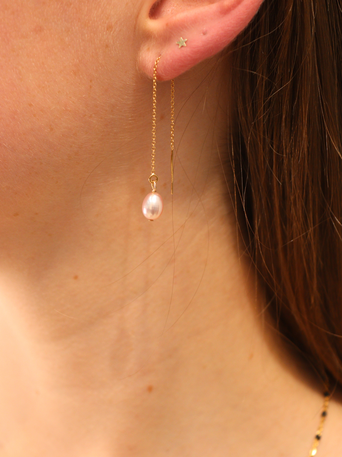 Close-up of gold threader earrings with pink freshwater pearl, handcrafted and elegant minimalist jewellery.