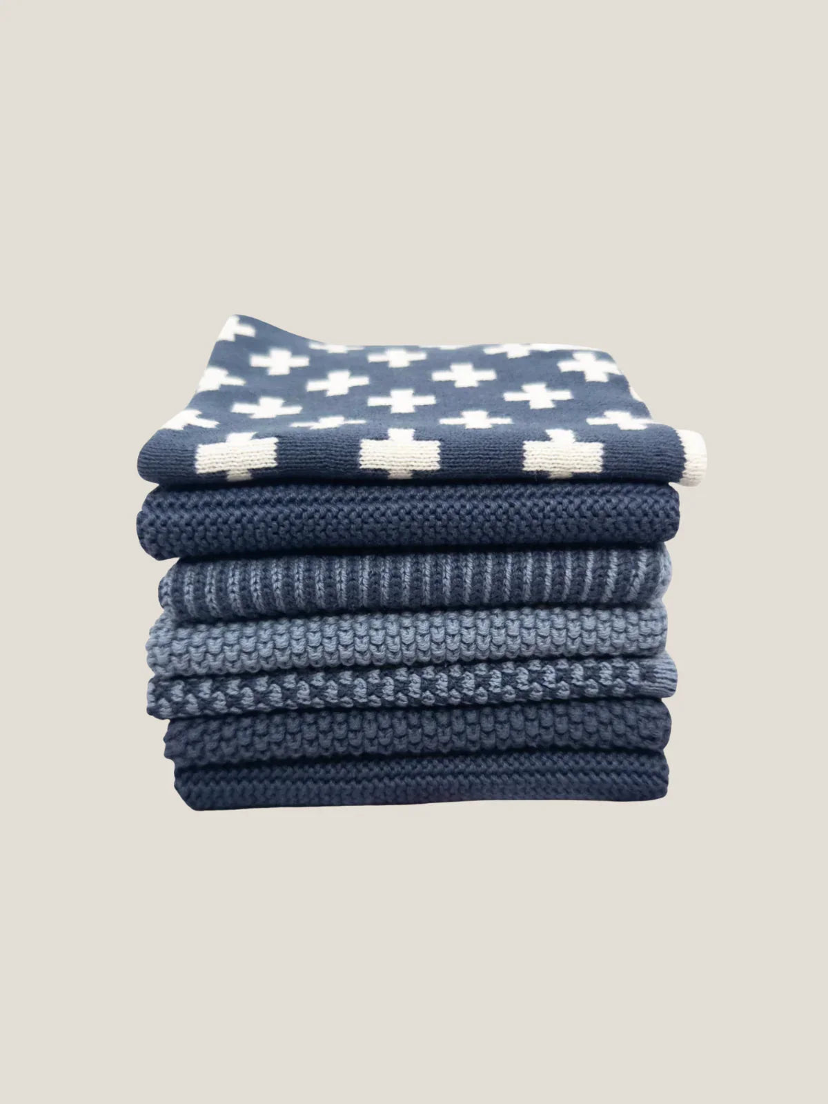 Stack of blue cotton dishcloth with white patterns on a beige background
