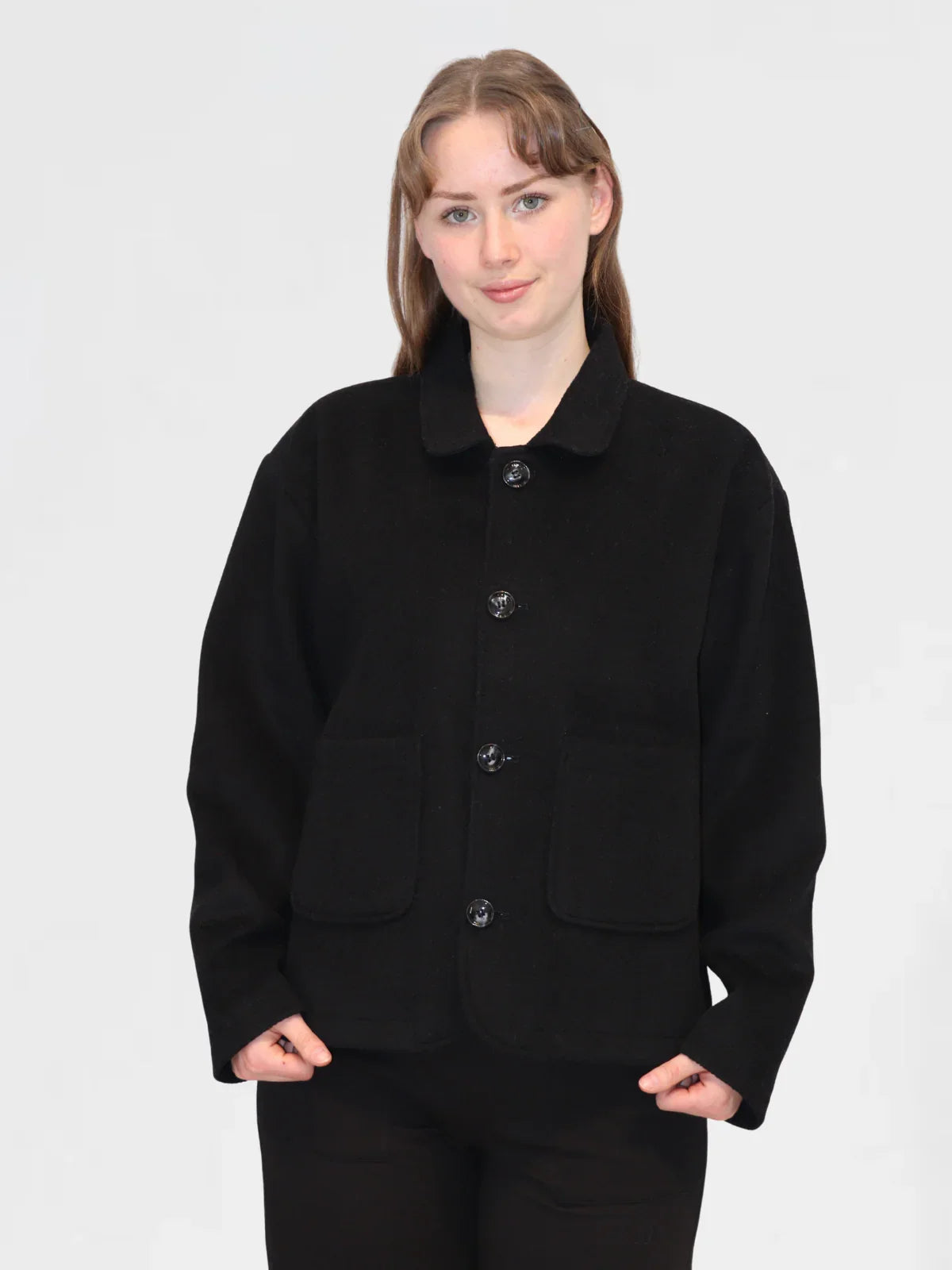 Person wearing a black wool jacket on a plain background