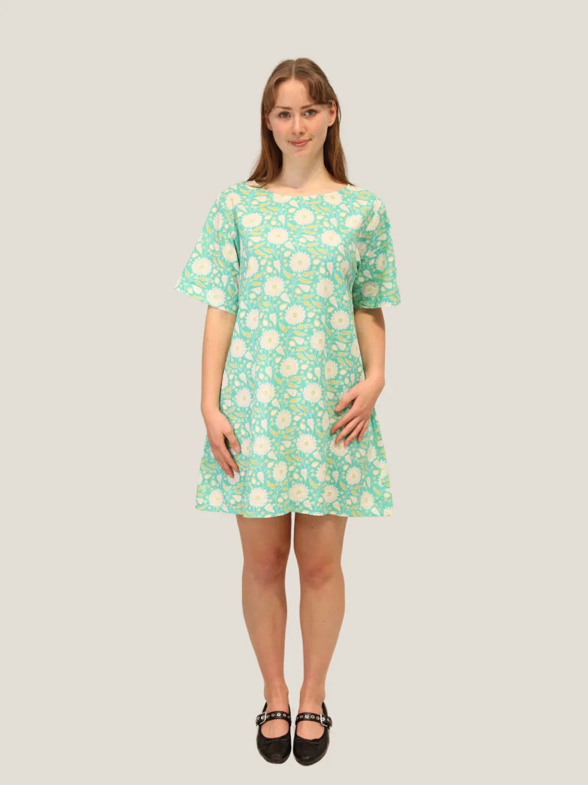 Woman wearing a green floral dress against a plain background