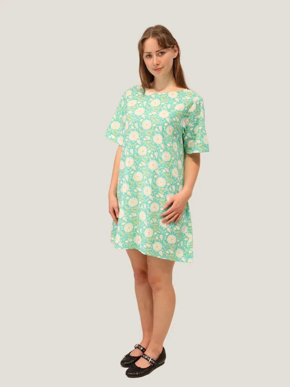 Woman wearing a green floral dress against a plain background