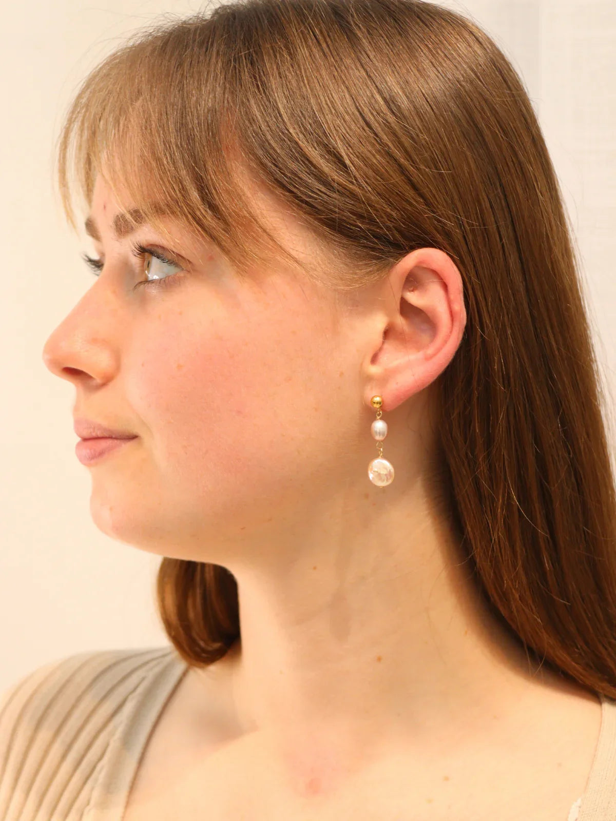 Woman wearing pearl earrings with a plain background