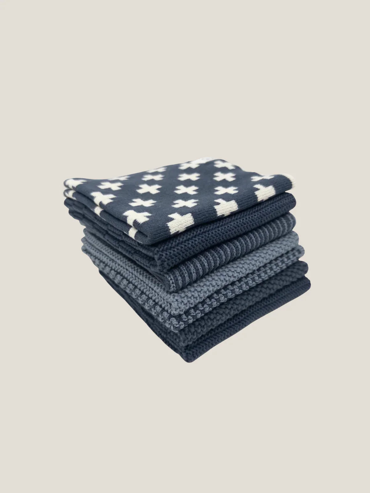 Stack of blue cotton dishcloth with white patterns on a beige background