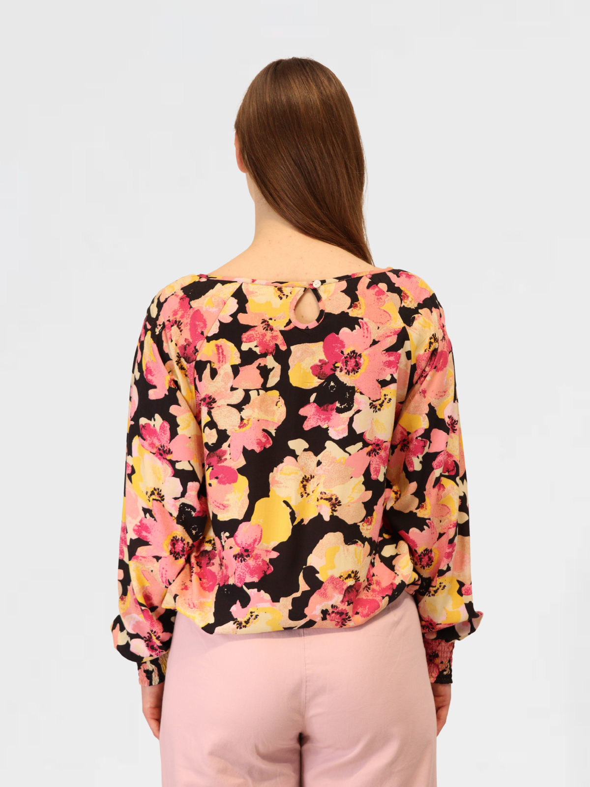 Close-up of floral blouse back showing keyhole neckline detail and bold pink floral print.
