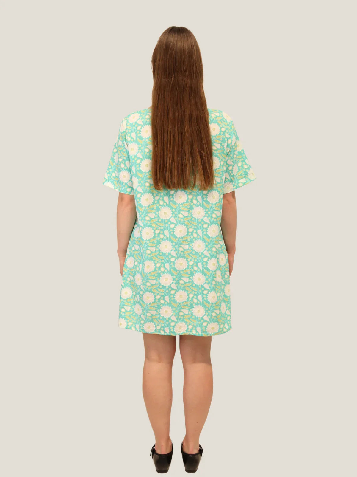 Person wearing a green floral dress on a plain background