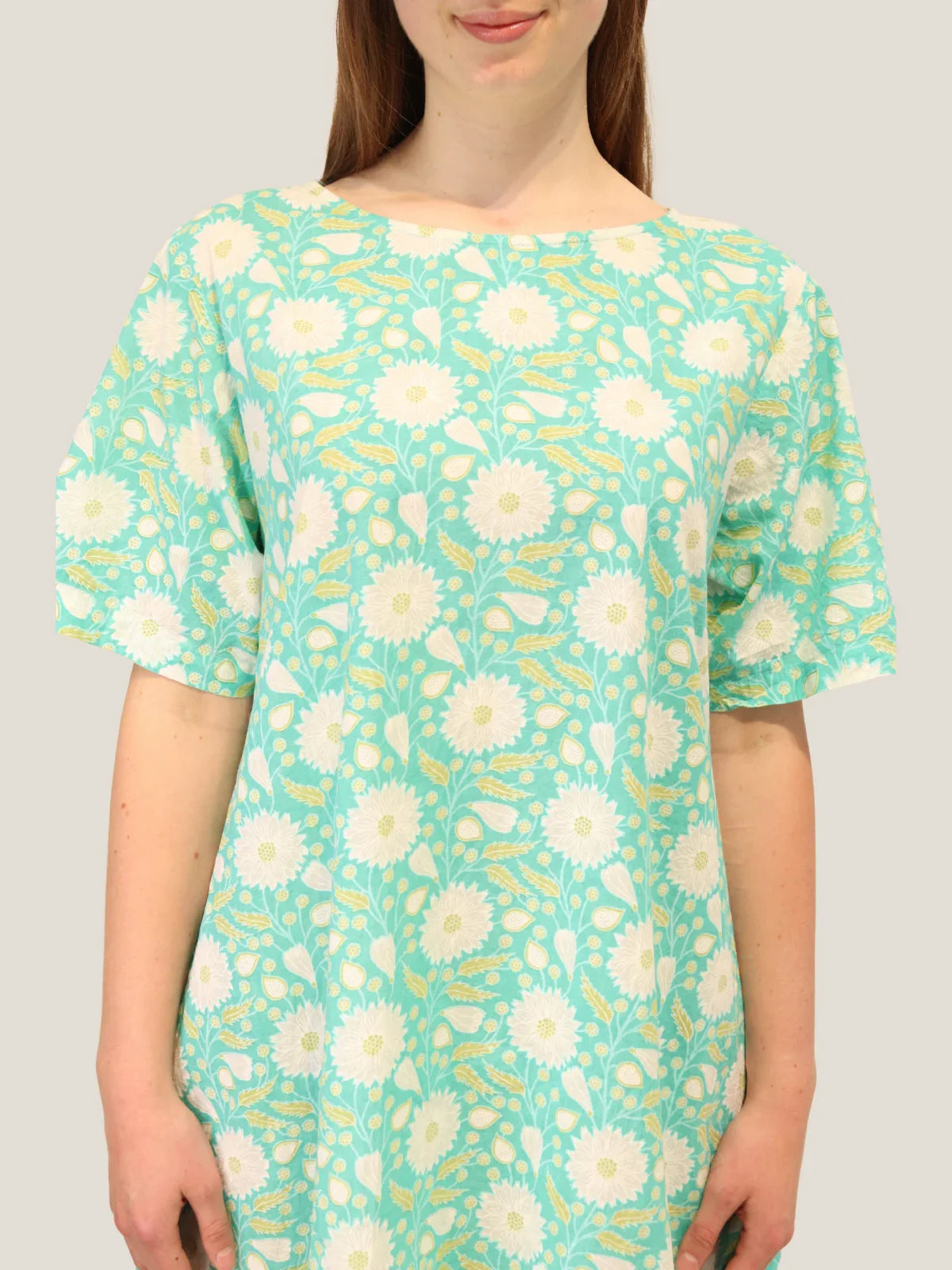 Woman wearing a floral dress with white flowers on a light green background