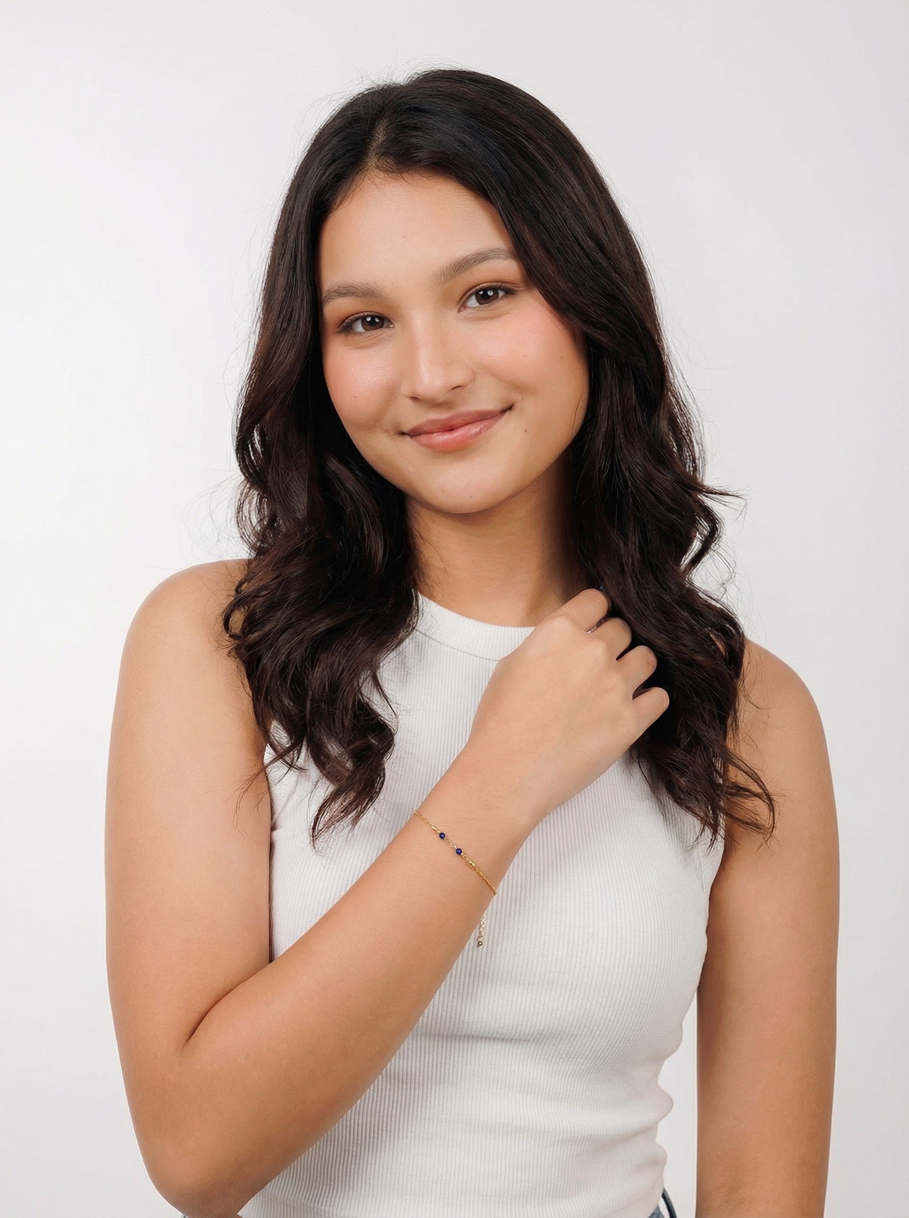 Woman in white sleeveless top wearing gold ethical bracelet, Reca jewelry product photo