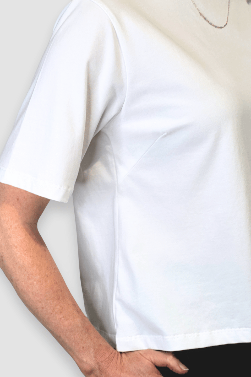 Close-up of a person wearing a plain white short-sleeve ethical cotton t-shirt from Reca