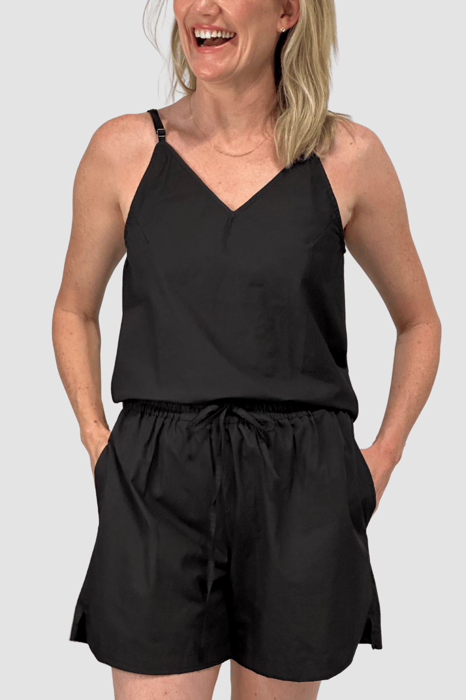 Woman wearing black cotton cami with adjustable straps and matching black shorts with drawstring