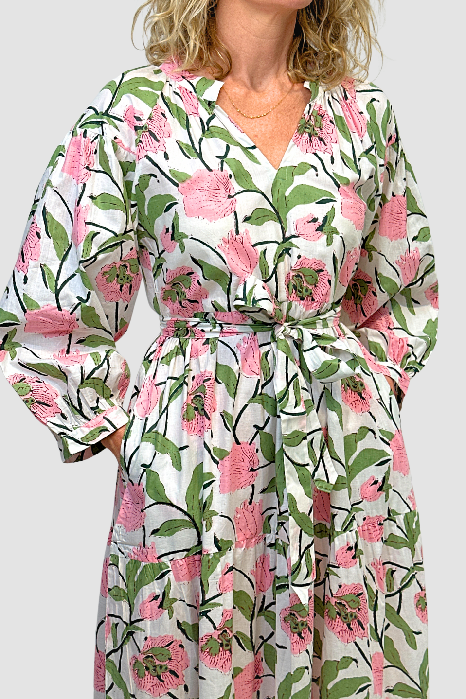 Woman wearing a Blossom Meadow Cotton Midi Dress that has pink flowers and green leaves on a white background