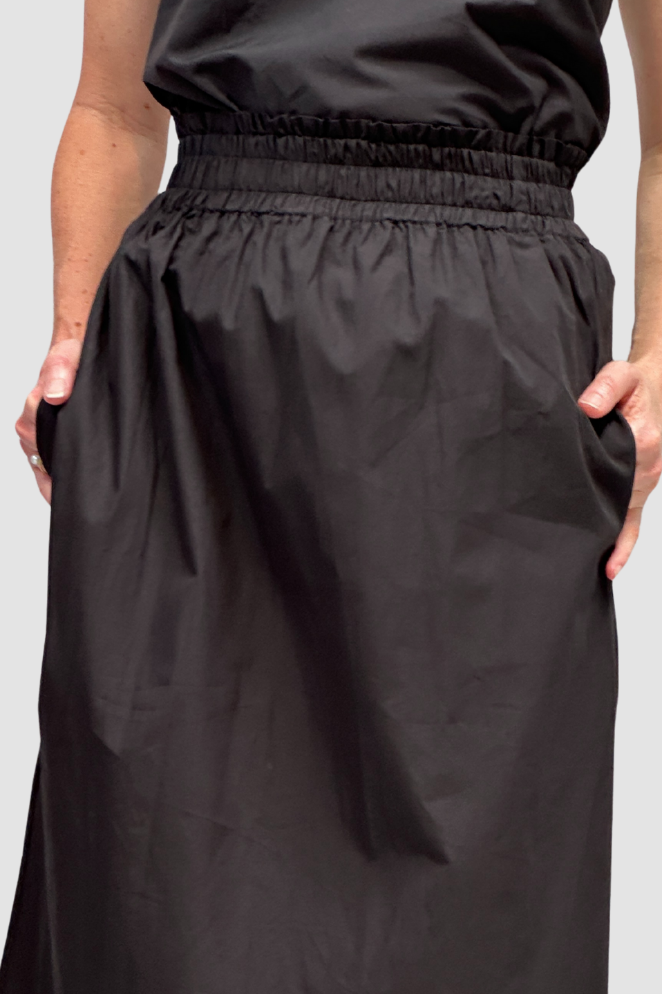 Black skirt worn by a person on a plain background