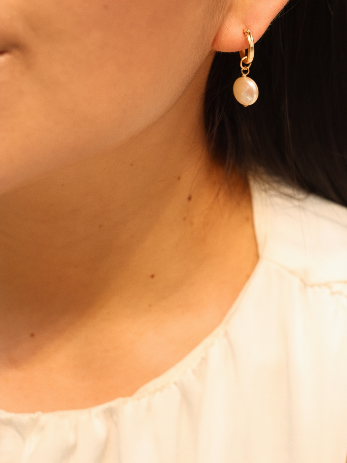 Pearl hoops earring worn by a person with a neutral background