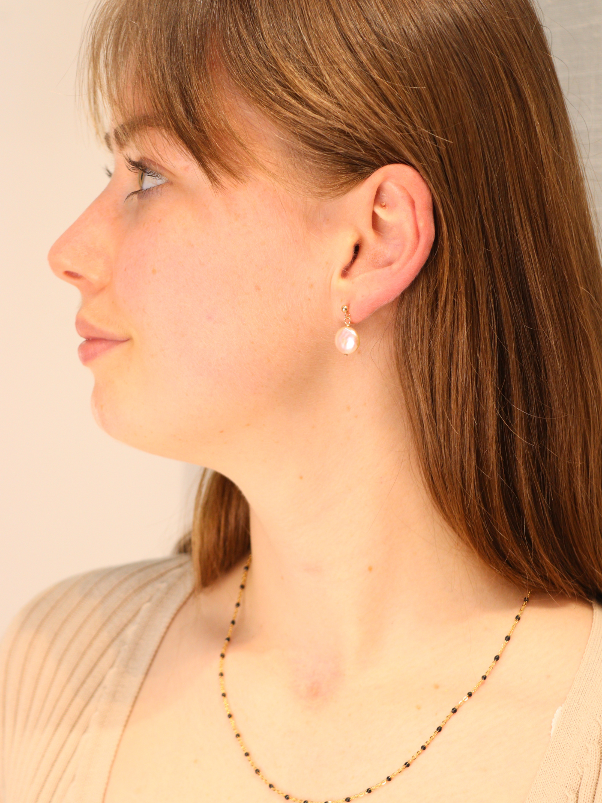 Woman wearing elegant gold pearl drop earrings.