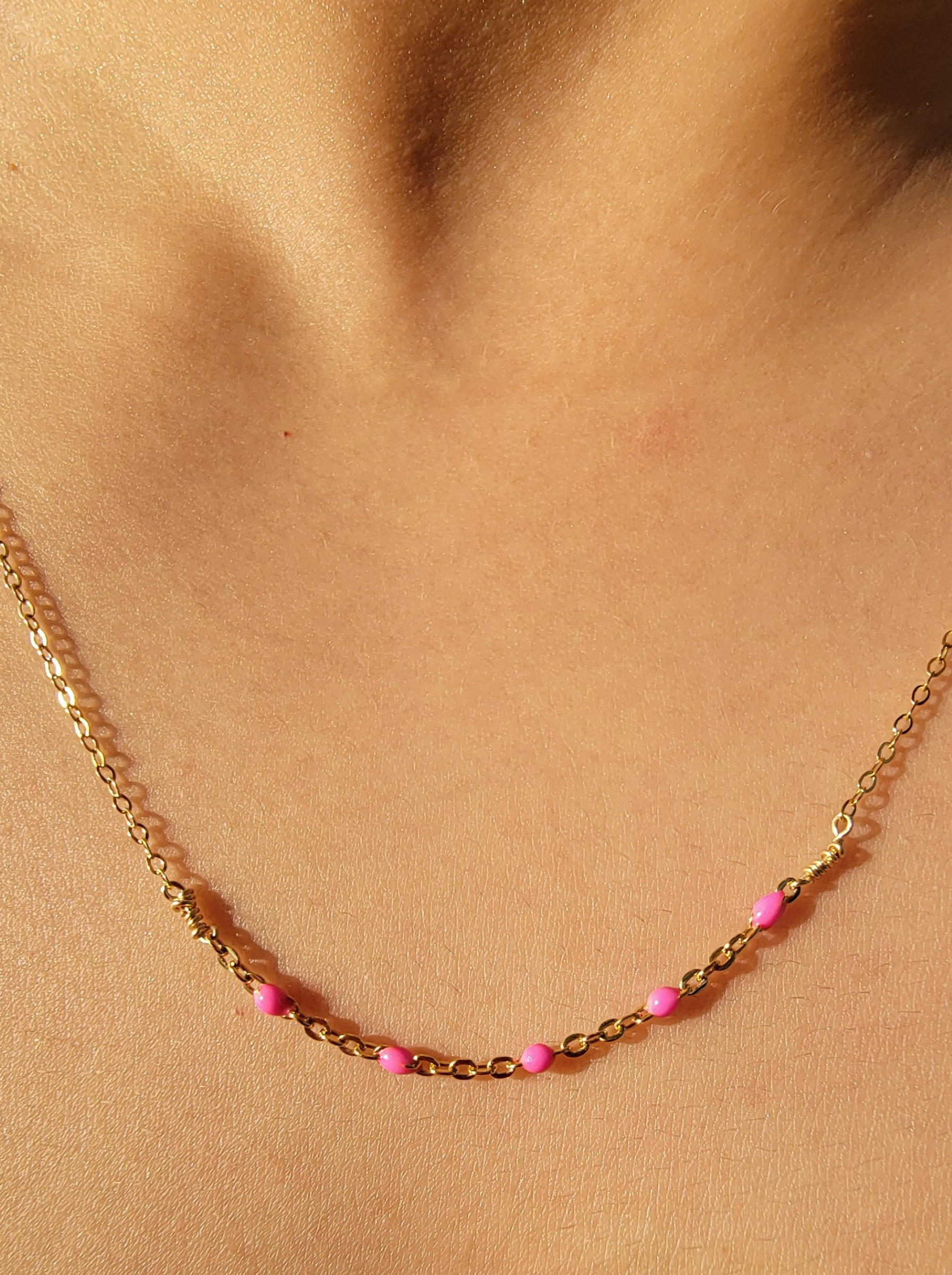 Necklace with Hot Pink Enamel Satellite Necklace on a person's neck against a beige background