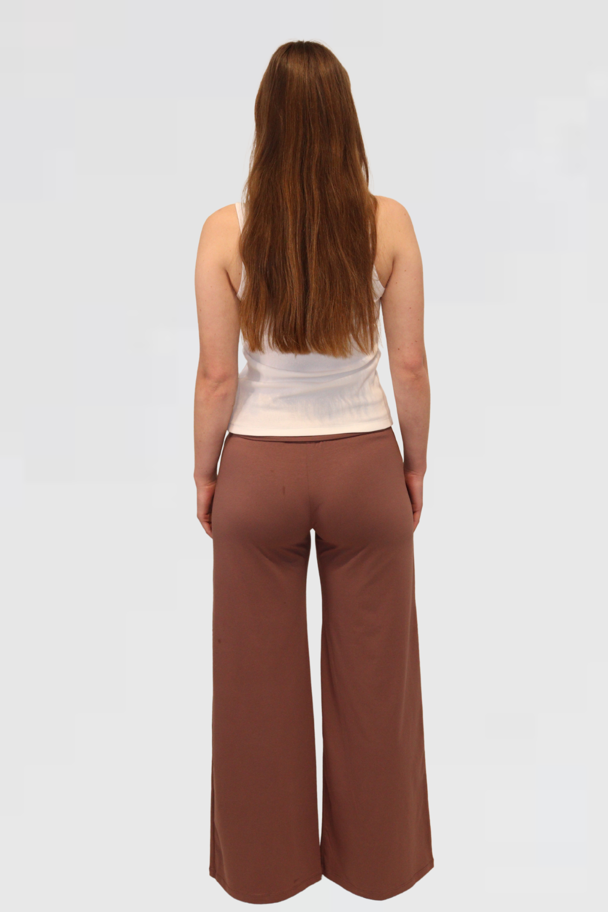 Woman wearing a beige sleeveless top and Leisure Lux Pants - Mocha Mousse on a white background