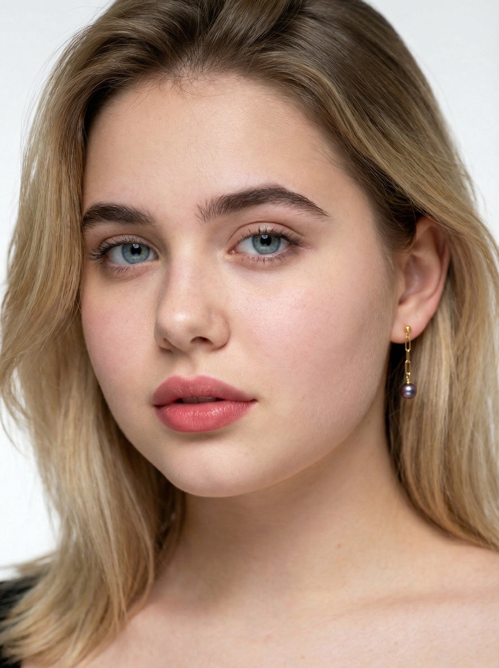 Close-up of a person with blonde hair and blue eyes wearing earrings.