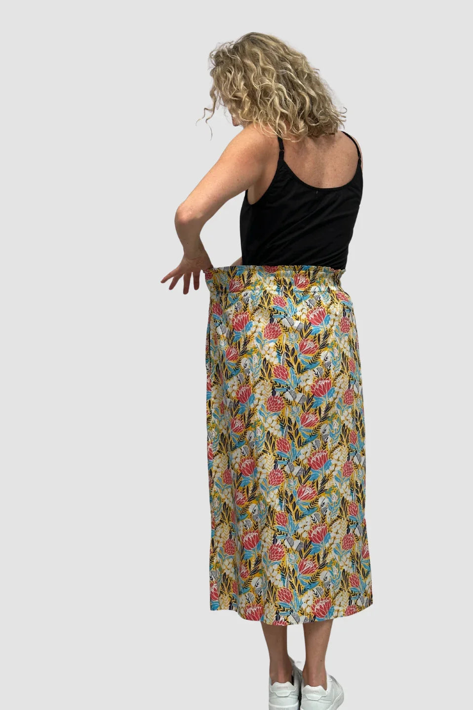 Woman wearing a colorful floral skirt on a plain background