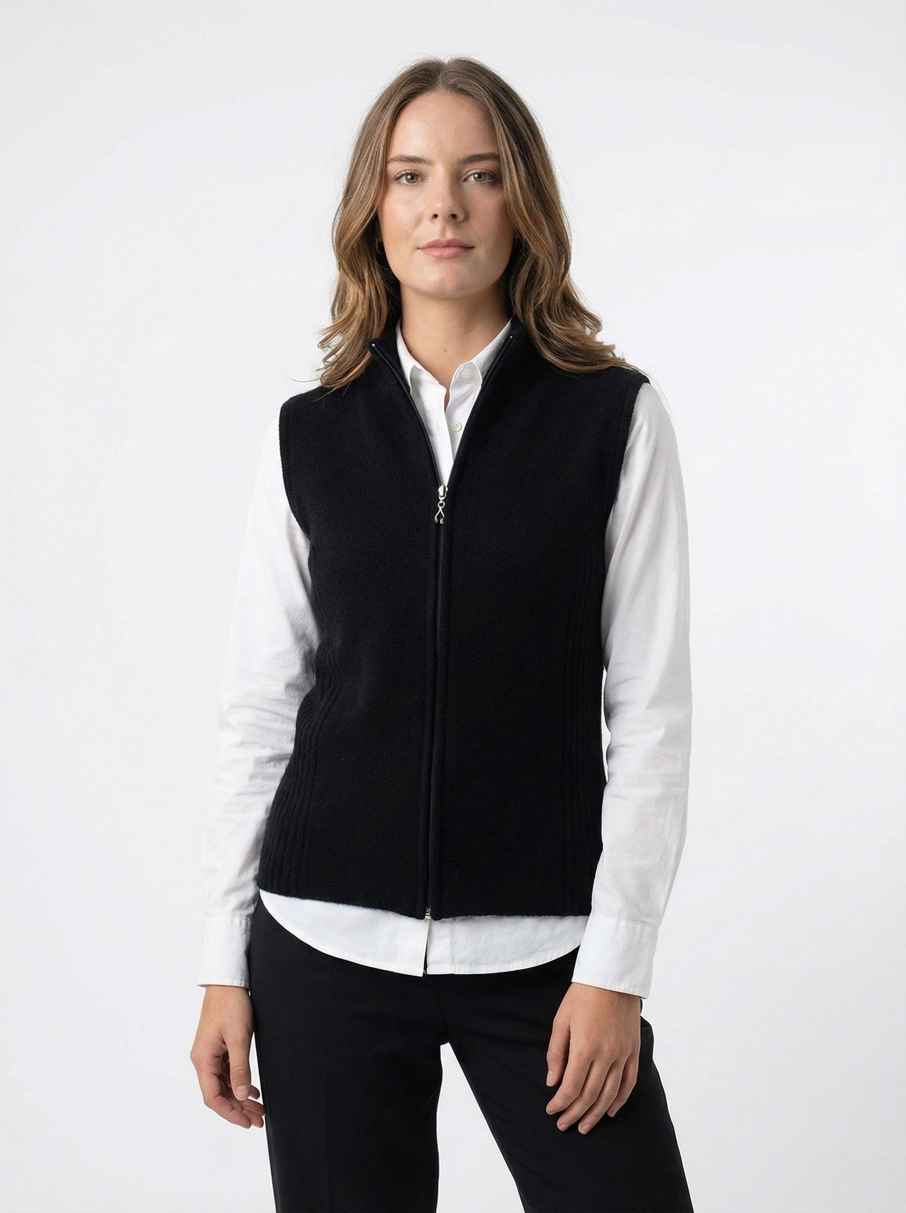 Woman wearing a Rib Zip Vest – Black over a white shirt on a white background