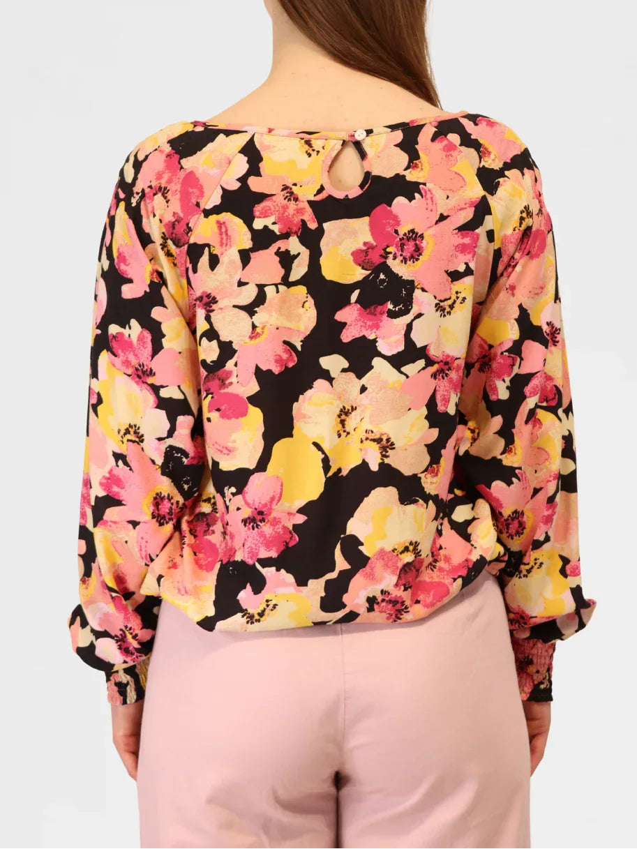 Close-up of floral blouse back showing keyhole neckline detail and bold pink floral print.