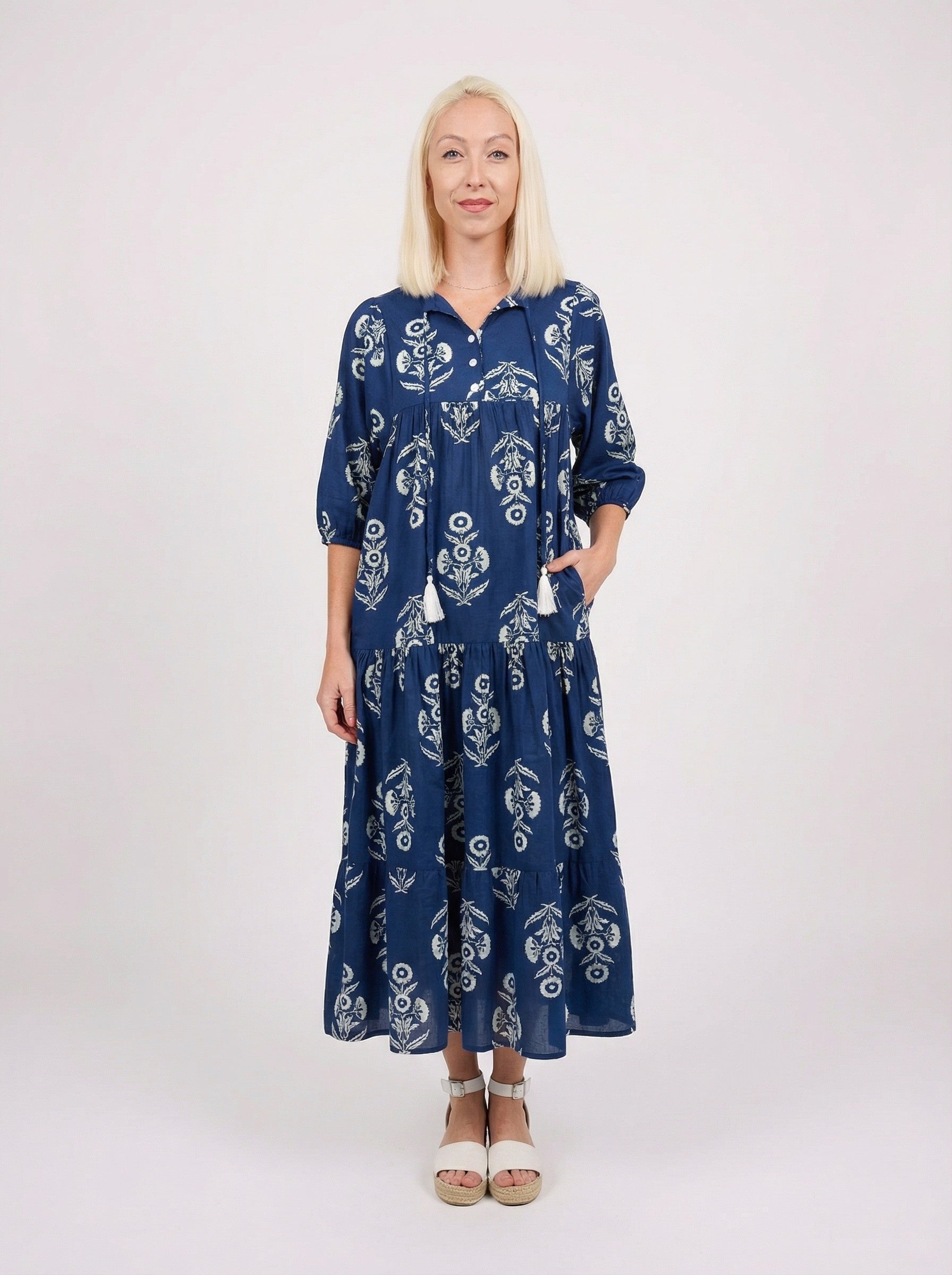 Woman wearing a blue patterned ( Wildflower) dress on a white background