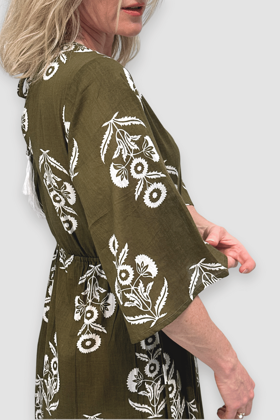 Woman wearing a green dress with white floral patterns on a plain background