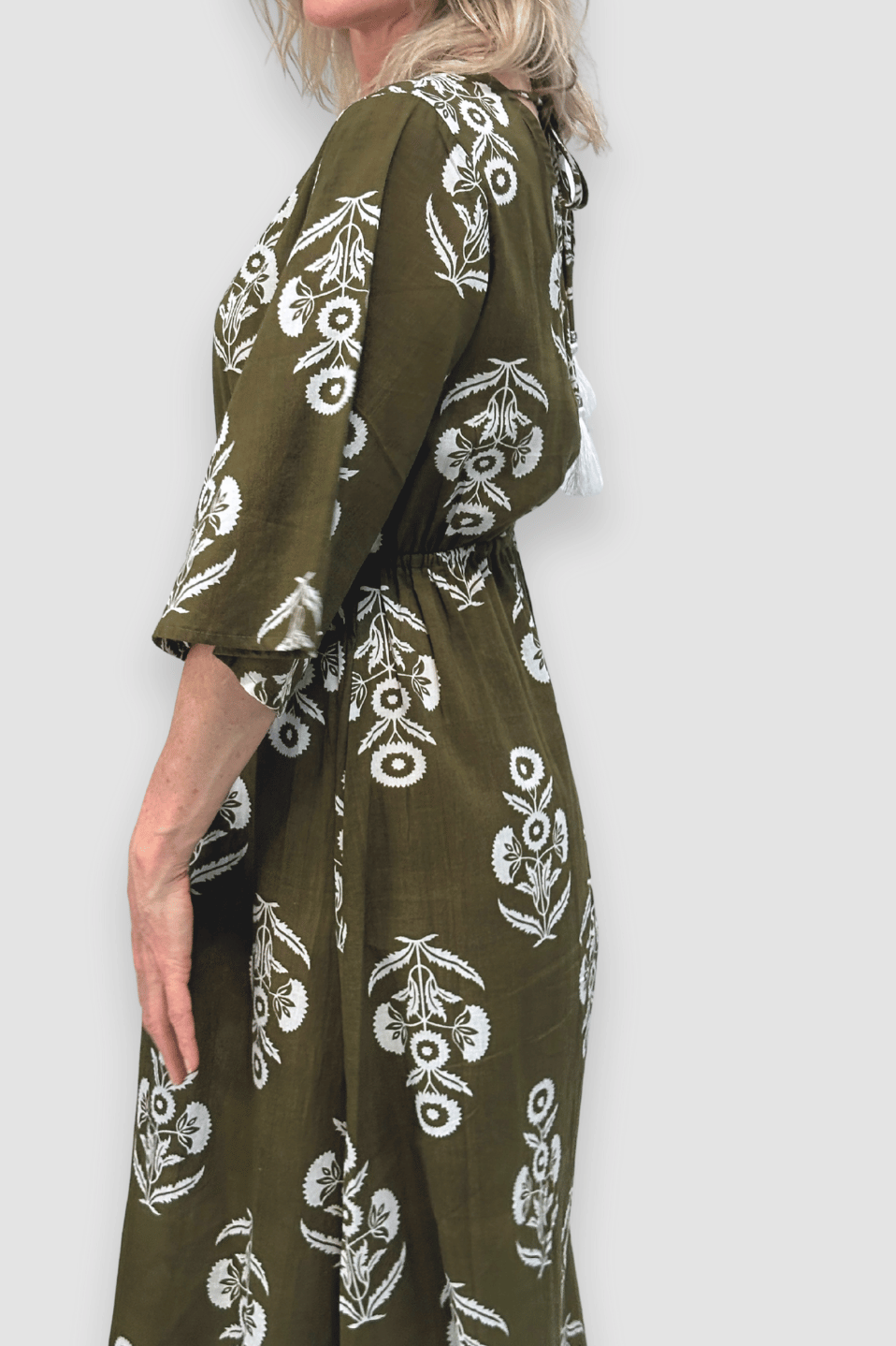 Woman wearing a green dress with white floral patterns on a plain background