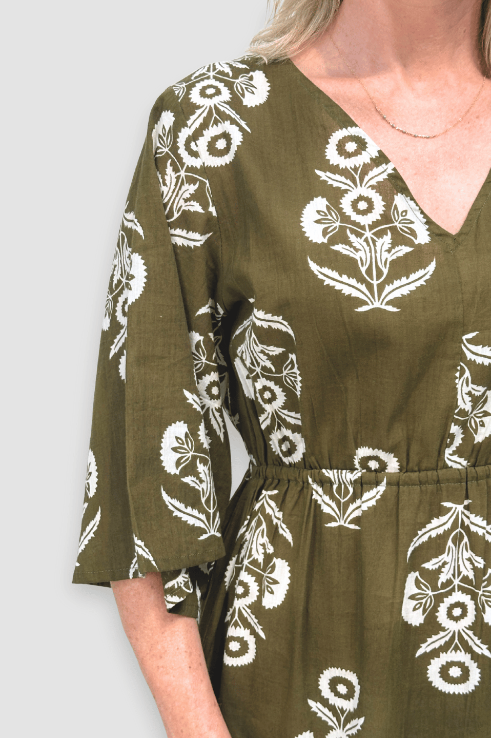 Green dress with white floral patterns on a plain background