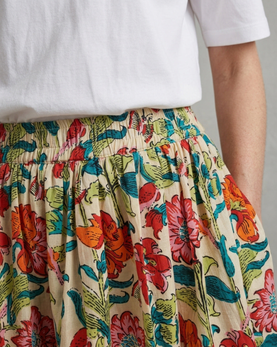 Fabric detail of the Bloomfield Garden Skirt, cream cotton printed with red, coral, teal and green florals below a shirred elasticated waistband