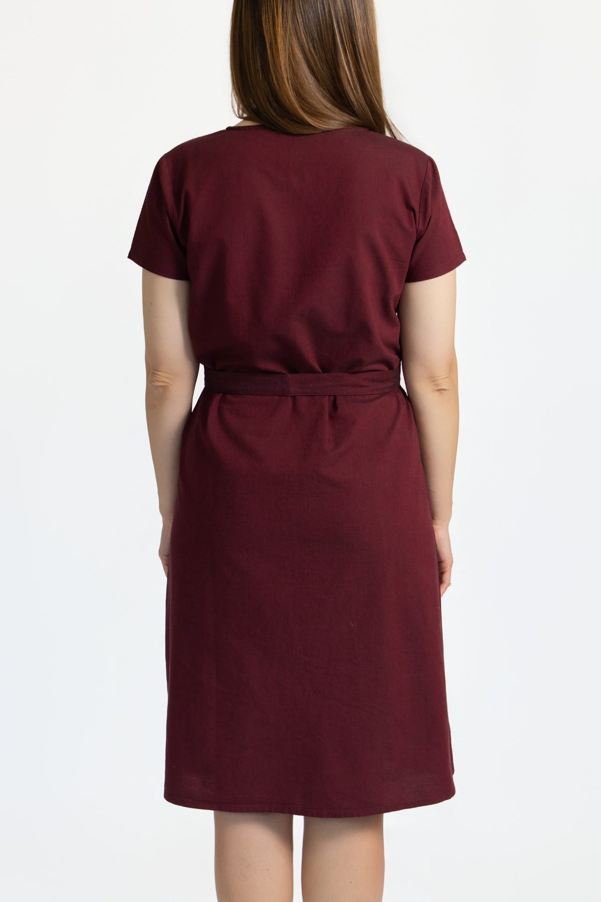 Back view of a burgundy linen cotton dress showing the removable waist belt and knee-length shape